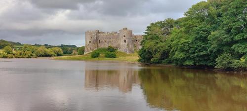 a castle sitting on the side of a river at Raymond House Guest House Penally in Penally