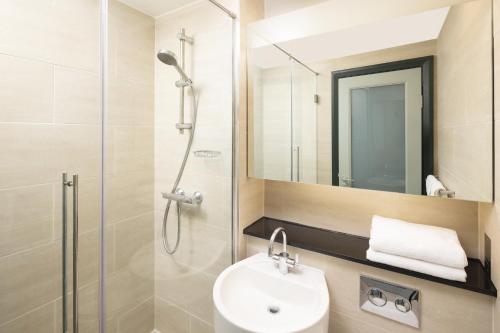 een badkamer met een douche, een wastafel en een spiegel bij Four Points by Sheraton Edinburgh in Edinburgh
