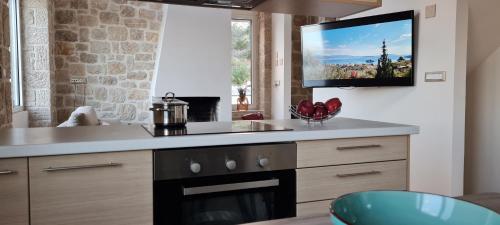 a kitchen with a stove and a tv on the wall at Πέτρα, Ελιά και Λεβάντα in Tolo