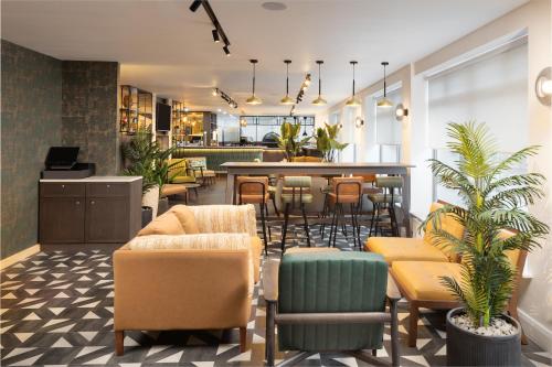 a lobby with chairs and a bar in the background at Four Points by Sheraton Edinburgh in Edinburgh