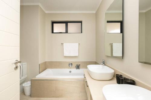 a bathroom with a white tub and a sink at Lux 2bed 20Mb WiFi on Keyes artmile 2km 2 Gautrain in Johannesburg