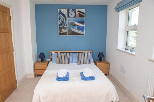 a blue bedroom with a bed with two towels on it at River View at White Horses, Bantham, South Devon with glorious estuary views in Bigbury on Sea