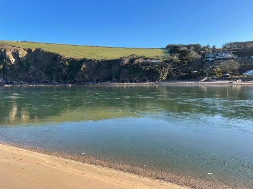 a body of water with a sandy beach and houses at River View at White Horses, Bantham, South Devon with glorious estuary views in Bantham