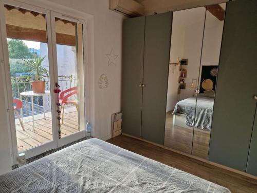 a bedroom with a large mirror and a bed and a balcony at jolie maison à 10 mn à pied du centre d'Aix-en-Provence in Aix-en-Provence