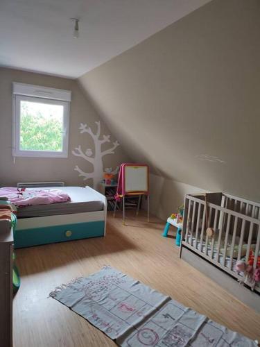 sypialnia z łóżeczkiem dziecięcym i drzewem na ścianie w obiekcie Maison individuelle 3 chambres w mieście Pleudihen-sur-Rance