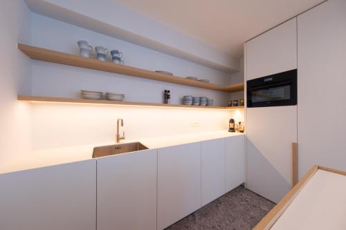 una cucina con armadi bianchi e lavandino di Luxury Design Apartment with free private parking a Ostenda