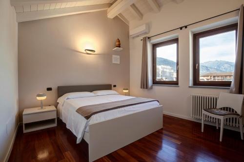 a white bedroom with a bed and two windows at DIMORA VERGER in Aosta