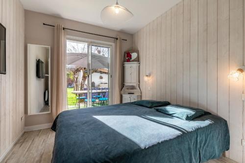 Un dormitorio con una cama y una ventana grande. en Landaise le lagunak avec piscine chauffée à 900 M de la plage, en Labenne
