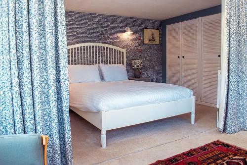 um quarto com uma cama branca e uma parede de tijolos em Cosy Cottage with Log Burner, Large Garden, Dog Friendly! em Monks Eleigh