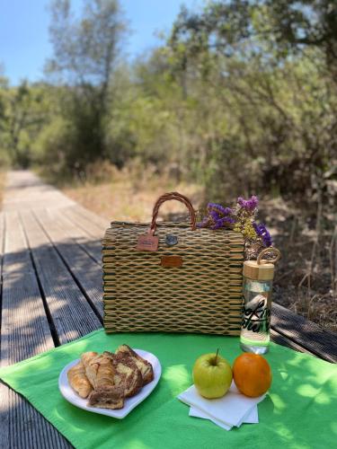 a picnic table with a basket and a plate of food at The Nest by Cooking and Nature in Alvados