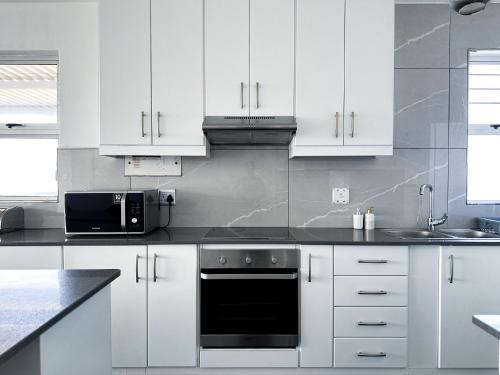 a kitchen with white cabinets and a black oven at 92 Camarque - 3 Bedroom Apartment With Amazing Sea Views In Umdloti in Umdloti