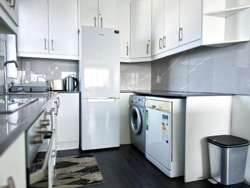 a kitchen with white cabinets and a washer and dryer at 92 Camarque - 3 Bedroom Apartment With Amazing Sea Views In Umdloti in Umdloti