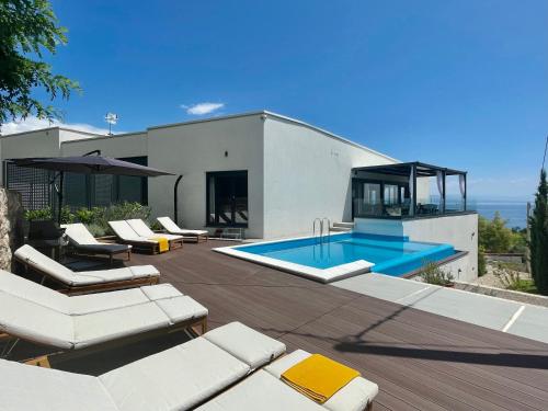 a house with a swimming pool and some lounge chairs at Villa Loqua, Seaview & Private Pool in Lovran
