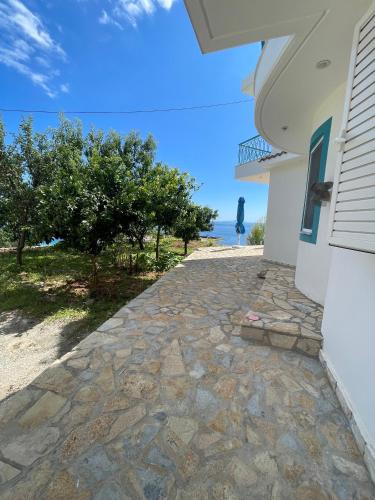 a stone walkway next to a house with the ocean at Endless blue Apartments in Dhërmi