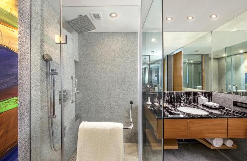 y baño con ducha acristalada y lavamanos. en DoubleTree by Hilton Ahmedabad en Ahmedabad