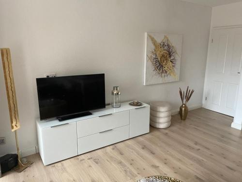 ein Wohnzimmer mit einem weißen Entertainment-Center mit einem Flachbild-TV in der Unterkunft Ferienwohnung Wagner in Borkum