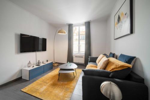 un salon avec un canapé noir et une télévision dans l'établissement Bright beautiful apartment - city center Cannes, à Cannes