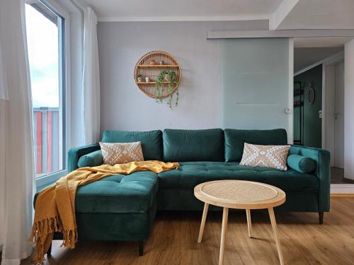 un sofá verde en una sala de estar con mesa en Tucan - Rooftop Terrace with View, BBQ, PS4+Stream, en Marburg an der Lahn