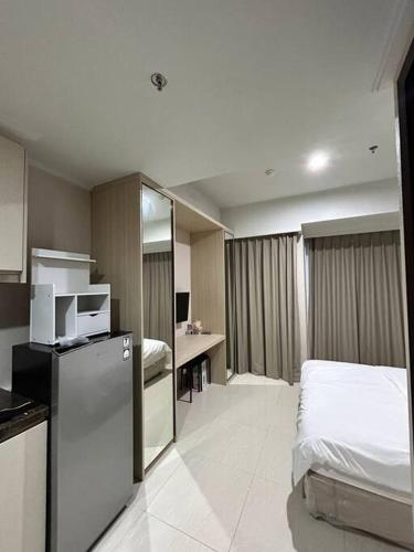 ein Hotelzimmer mit einem Bett und einem Kühlschrank in der Unterkunft Green Sedayu Apartment - Studio By PSG Grup in Jakarta
