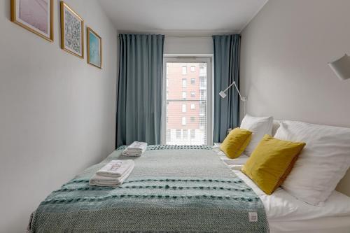 a bedroom with a bed with yellow pillows and a window at Chmielna Park 5 TriApart® in Gdańsk