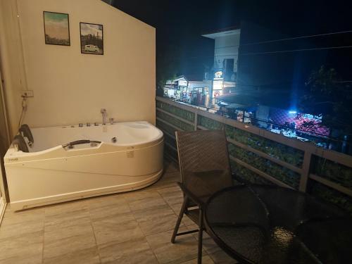 a bathroom with a tub and a table and a chair at Bonsai Jacuzzi Suites in Panglao