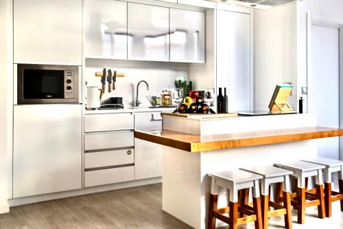een keuken met witte kasten en barkrukken bij Cristalia,Roof terrace in city center, Garage, Netflix 75inch TV in Funchal