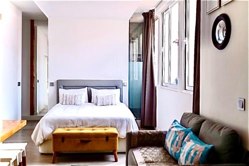 een slaapkamer met een bed en een bank bij Cristalia,Roof terrace in city center, Garage, Netflix 75inch TV in Funchal