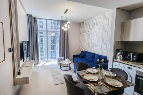 a living room with a table and a blue couch at STAY BY LATINEM Luxury 1BR Holiday Home CVR A703 near Burj Khalifa in Dubai