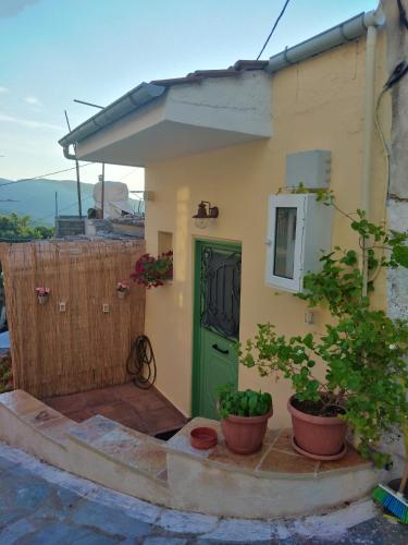 una piccola casa con una porta verde e piante in vaso di ilianas place ad Ágios Matthaíos