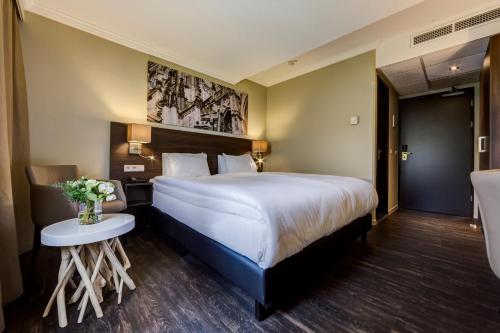 una habitación de hotel con una cama grande y una mesa en Fletcher Hotel-Restaurant ‘s-Hertogenbosch, en Den Bosch