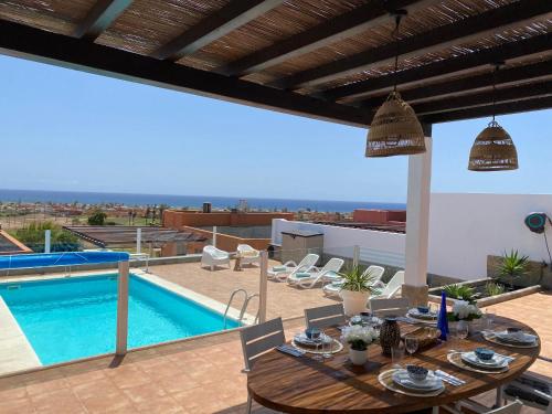 a patio with a table and a swimming pool at Casa Blanca Caleta - Golf & Sea Views - private heated Saltwater Pool - BBQ - Aircondition" in Caleta De Fuste