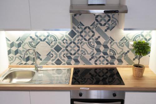 a kitchen with a sink and a tile wall at antica dogana apartments scirocco in Terracina