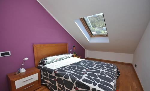 a bedroom with a bed with purple walls and a window at Acogedor ático a pie de mar y montaña. in O Pindo