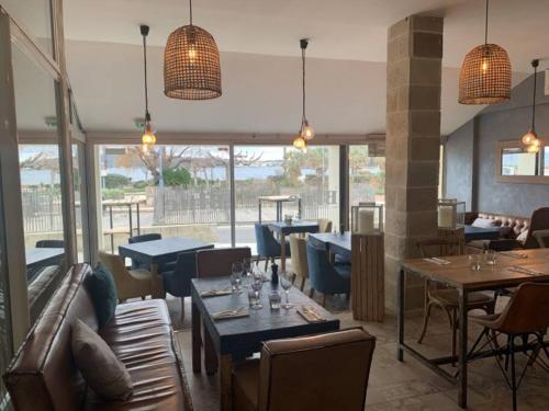 un restaurant avec des tables, des chaises et des fenêtres dans l'établissement Studio ZEN SUD Plage à pied Pin Rolland Sablettes, à Saint-Elme