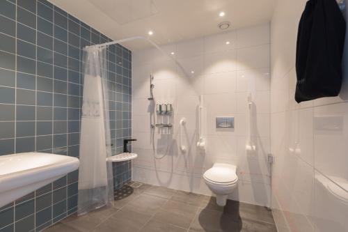 a bathroom with a shower and a toilet and a sink at Hampton By Hilton Utrecht Centraal Station in Utrecht