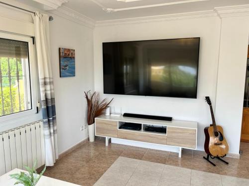 un soggiorno con TV a schermo piatto e chitarra di Casa Rose - 4-Bed villa with private pool in Calpe a Calpe