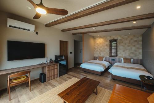 um quarto de hotel com duas camas e uma televisão de ecrã plano em L'isola THE BIRD em Kami Amakusa