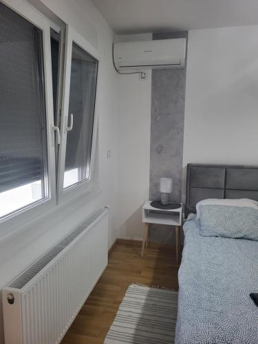 um pequeno quarto com uma cama e uma janela em Apartman Mima em Sombor