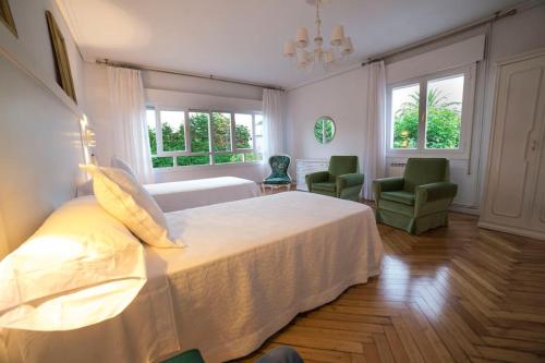 a bedroom with a large white bed and two chairs at Villa Anievas in Boó de Piélagos