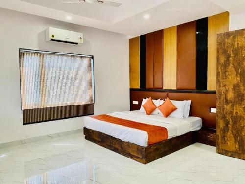 a bedroom with a bed with orange and white pillows at Hotel Haridwar in Haridwār