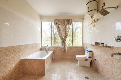 baño con bañera, aseo y ventana en Rustica Villa By JadeCaps 7BHK 2Pvt Pool Projector en Denkanikottai