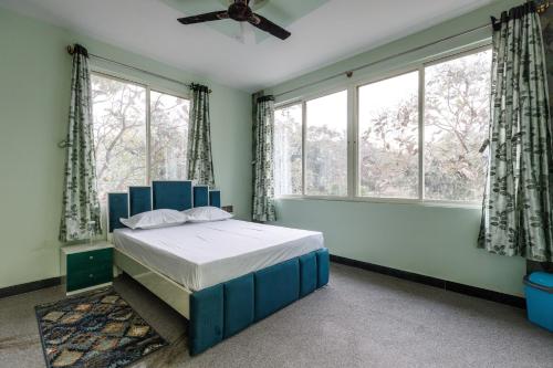 1 dormitorio con 1 cama azul frente a las ventanas en Rustica Villa By JadeCaps 7BHK 2Pvt Pool Projector en Denkanikottai