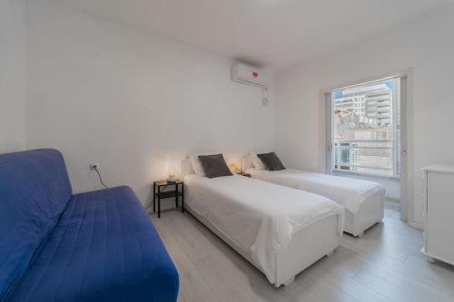 1 dormitorio con 2 camas y sofá azul en Beachfront apartment with breathtaking sea view, en Netanya