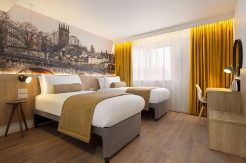 a hotel room with two beds with yellow curtains at Super 8 by Wyndham Chester East in Chester