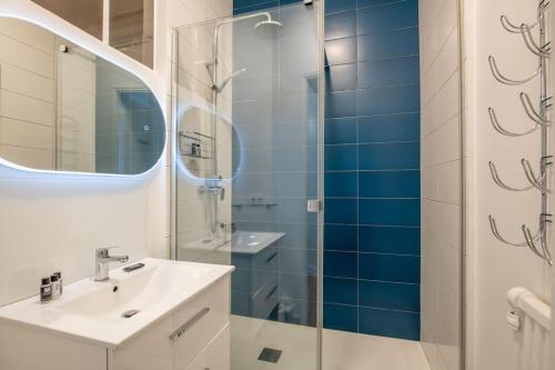 a bathroom with a sink and a shower with blue tiles at République - Magnifique appartement au centre de Paris in Paris