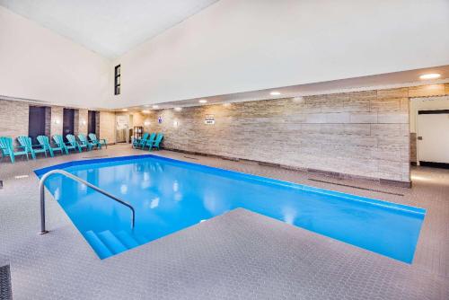 a large swimming pool with blue chairs and a brick wall at Travelodge by Wyndham Miramichi New Brunswick in Miramichi