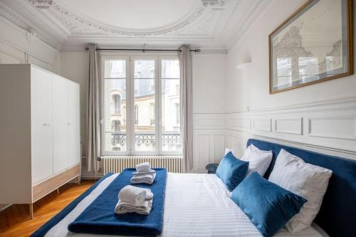 a bedroom with a blue and white bed with towels on it at République - Magnifique appartement au centre de Paris in Paris