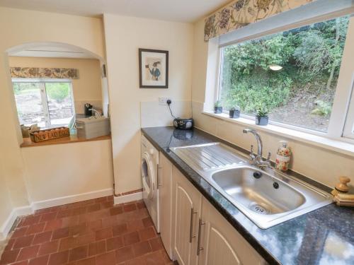 cocina con fregadero y ventana en Grove Cottage, en Leominster