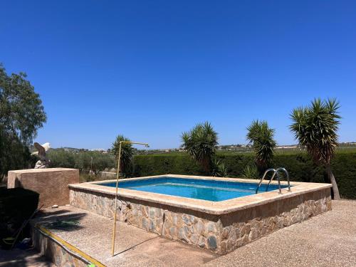 a swimming pool with a stone wall around it at Villa con piscina y jardines privados in Bullas