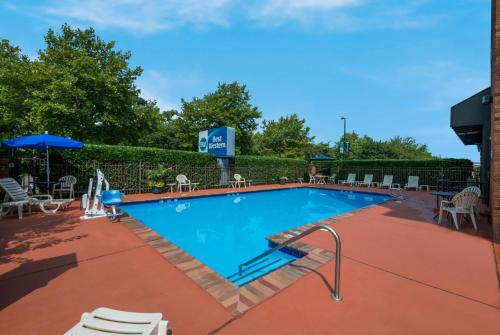 una piscina en un complejo con sillas y sombrillas en Best Western Hampton Coliseum Inn, en Hampton